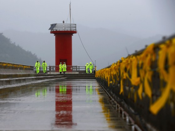 Police officers stand guard at pier, as yellow ribbons dedicated to missing and dead passengers on board capsized Sewol ferry are tied to handrails, at a port in Jindo