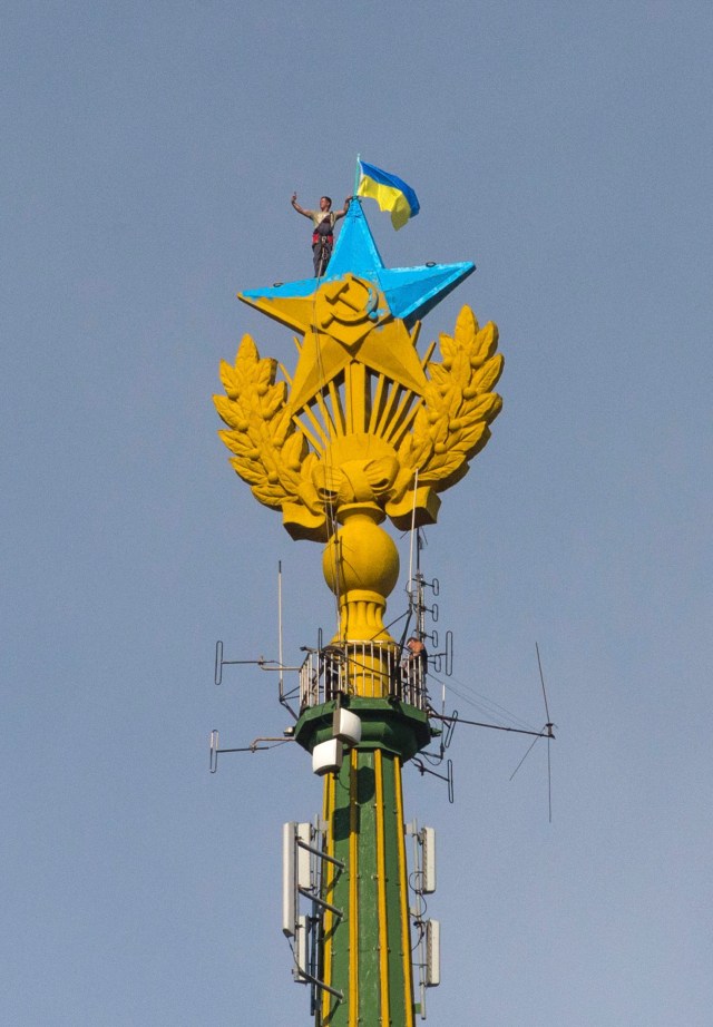 A man takes a "selfie" as he stands with a Ukrainian flag on a Soviet-style star re-touched with blue paint so it resembles the yellow-and-blue national colours of Ukraine, atop the spire of a building in Moscow