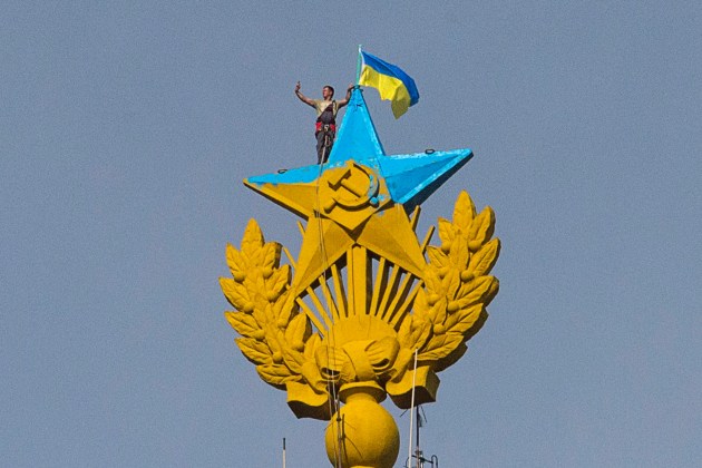 A man takes a "selfie" as he stands with a Ukrainian flag on a Soviet-style star re-touched with blue paint so it resembles the yellow-and-blue national colours of Ukraine, atop the spire of a building in Moscow