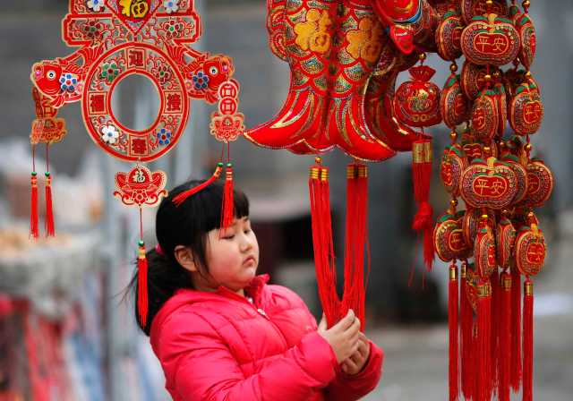 A girl looks at traditional decorations for the upcoming Chinese Lunar New Year celebrations at a market in Beijing