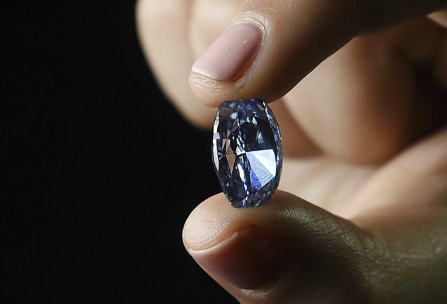 Una empleada de la casa de subastas Sotheby's sostiene un diamante azul de la colección Milenio de De Beers, en Londres, Reino Unido, hoy, 15 de marzo de 2016. La pieza, de 10,10 quilates, saldrá a la venta en Hong Kong el próximo 5 de abril. EFE/ANDY RAIN