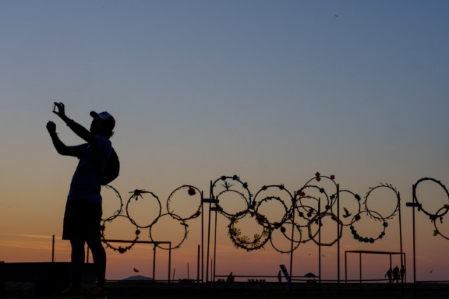 A man takes a selfie in front of Olympic rings made of recycled materials at Copacabana beach in Rio de Janeiro, Brazil, in the early morning of July 24, 2016. The Rio 2016 Olympic and Paralympic Games will be held in Brazil from August 5-21 and September 7-18 respectively. / AFP PHOTO / YASUYOSHI CHIBA