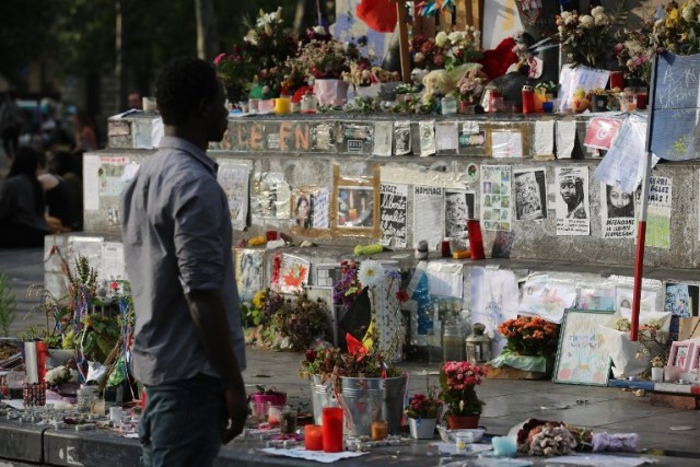 A man stands in front of French flags and messages displayed at the place de la Republique's monument in Paris, on July 26, 2016 after a priest was killed in the Normandy city of Saint-Etienne-du-Rouvray in the latest of a string of attacks against Western targets claimed by or blamed on the Islamic State jihadist group. One of the two attackers who stormed a church in France and slit a priest's throat on July 26 had been charged with terror links and held before being freed on bail, a source close to the investigation said. / AFP PHOTO / GEOFFROY VAN DER HASSELT