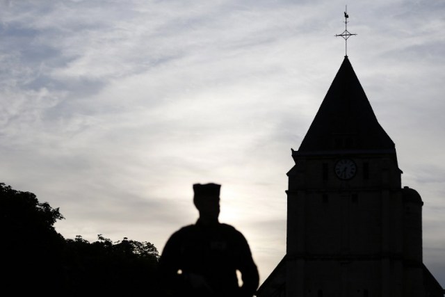 A Police officer stand guards the Saint-Etienne church on July 27, 2016 in Saint-Etienne-du-Rouvray, 125 kilometres (77 miles) north of Paris, in the latest of a string of attacks against Western targets claimed by or blamed on the Islamic State jihadist group. Father Jacques Hamel, a semi-retired assistant parish priest, had his throat slit in a church in northern France on July 26, 2016, after two men stormed the building and took hostages. As the two attackers made to leave the church they were confronted by a French police unit specialising in hostage situations, the BRI, and were shot dead. / AFP PHOTO / CHARLY TRIBALLEAU