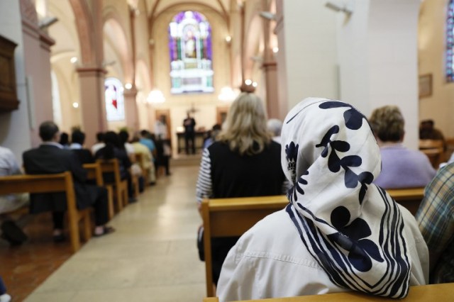 A Muslim faithful woman sits as she attends a Mass in tribute to priest Jacques Hamel at the Saint-Leu ? Saint-Gilles Bagnolet's Church, near Paris, on July 31, 2016. Muslims across France were invited to participate in Catholic ceremonies today to mourn a priest whose murder by jihadist teenagers sparked fears of religious tension. Masses will be celebrated across the country in honour of octogenarian Father Jacques Hamel, whose throat was cut in his church on July 26, 2016 in the latest jihadist attack on France. / AFP PHOTO / Thomas SAMSON