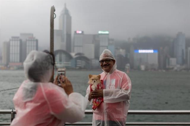 Un hombre posa para una foto con su mascota en el puerto Victoria afectado por los fuertes vientos del tifón Nida hoy, martes 2 de agosto de 2016, en Hong Kong (China). Nida es el primer gran tifón que golpea Hong Kong este año. EFE/JEROME FAVRE