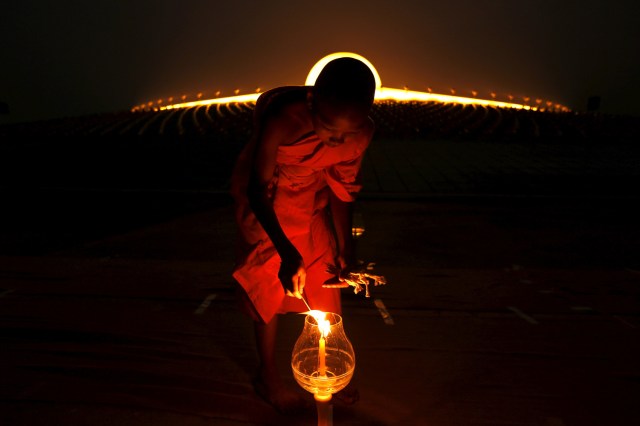 FILE PHOTO - A Buddhist monk lights a candle at Wat Phra Dhammakaya during a ceremony on Makha Bucha Day in Pathum Thani province, north of Bangkok February 22, 2016. REUTERS/Jorge Silva/File Photo REUTERS PICTURES OF THE YEAR 2016 - SEARCH 'POY 2016' TO FIND ALL IMAGES