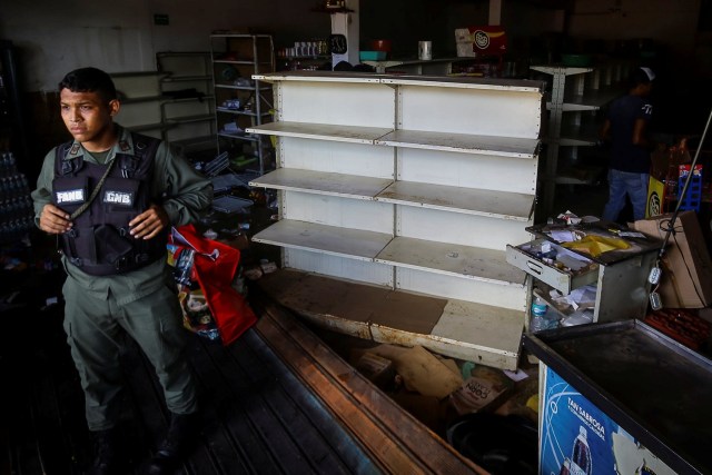 A Venezuelan National Guard stands guard as workers recover the valuables after a supermarket was looted in Ciudad Bolivar, Venezuela December 19, 2016. REUTERS/William Urdaneta EDITORIAL USE ONLY. NO RESALES. NO ARCHIVE.
