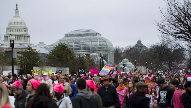Demonstrators march past the US Capitol (L) on the National Mall in Washington, DC, for the Women's march on January 21, 2017. Hundreds of thousands of protesters spearheaded by women's rights groups demonstrated across the US to send a defiant message to US President Donald Trump. / AFP PHOTO / JIM WATSON