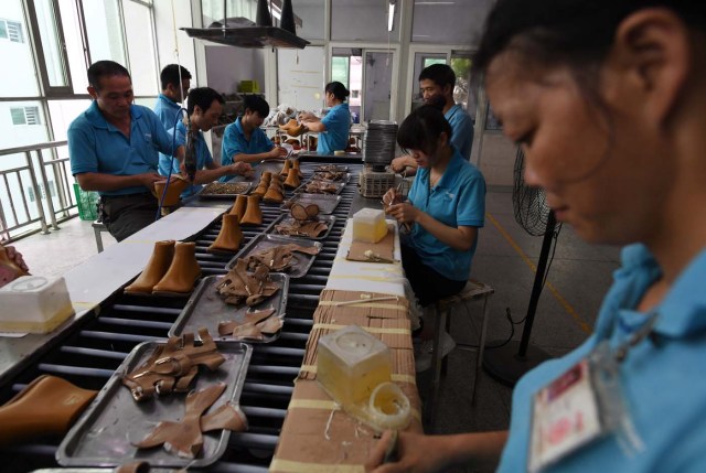 (FILES) This file photo taken on September 14, 2016 shows workers on a production line at the Huajian shoe factory, where about 100,000 pairs of Ivanka Trump-branded shoes have been made over the years amongst other brands, in Dongguan in south China's Guangdong province. In his January inauguration speech, US President Donald Trump made a seemingly straightforward pledge: "We will follow two simple rules: buy American and hire American." His daughter is the exception: even as he spoke, at least eight shipments of Ivanka Trump-branded shoes, bags and clothes -- more than 53.5 tonnes -- were steaming towards American ports from China, according to US Customs bills of lading examined by AFP. / AFP PHOTO / Greg Baker / TO GO WITH China-US-politics-economy-trade-Trump, FOCUS by Ben DOOLEY