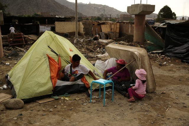Family stands outside a tent after rivers breached their banks due to torrential rains, causing flooding and widespread destruction in Huachipa, Lima, Peru, March 24, 2017. REUTERS/Mariana Bazo