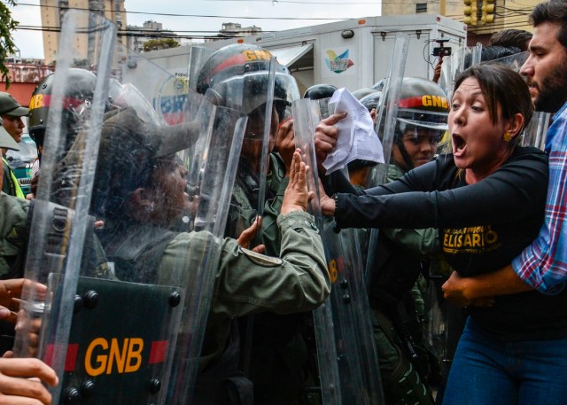 TOPSHOT - Venezuelan opposition deputy Amelia Belisario (2nd-R) scuffles with National Guard personnel in riot gear during a protest in front of the Supreme Court in Caracas on March 30, 2017. Venezuela's Supreme Court took over legislative powers Thursday from the opposition-majority National Assembly, whose speaker accused leftist President Nicolas Maduro of staging a "coup." / AFP PHOTO / JUAN BARRETO