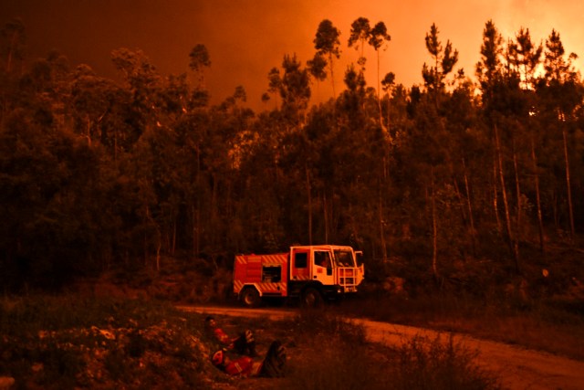 Firefighters rest during a wildfire at Penela, Coimbra, central Portugal, on June 18, 2017. A wildfire in central Portugal killed at least 25 people and injured 16 others, most of them burning to death in their cars, the government said on June 18, 2017. Several hundred firefighters and 160 vehicles were dispatched late on June 17 to tackle the blaze, which broke out in the afternoon in the municipality of Pedrogao Grande before spreading fast across several fronts. / AFP PHOTO / PATRICIA DE MELO MOREIRA