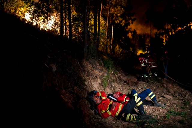 Firefighters rest during a wildfire at Penela, Coimbra, central Portugal, on June 18, 2017. A wildfire in central Portugal killed at least 25 people and injured 16 others, most of them burning to death in their cars, the government said on June 18, 2017. Several hundred firefighters and 160 vehicles were dispatched late on June 17 to tackle the blaze, which broke out in the afternoon in the municipality of Pedrogao Grande before spreading fast across several fronts. / AFP PHOTO / PATRICIA DE MELO MOREIRA