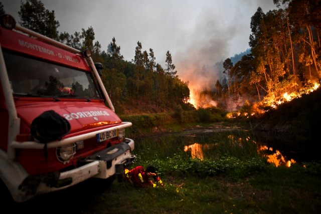 A firefighter rests next to fire combat truck during a wildfire at Penela, Coimbra, central Portugal, on June 18, 2017. A wildfire in central Portugal killed at least 25 people and injured 16 others, most of them burning to death in their cars, the government said on June 18, 2017. Several hundred firefighters and 160 vehicles were dispatched late on June 17 to tackle the blaze, which broke out in the afternoon in the municipality of Pedrogao Grande before spreading fast across several fronts. / AFP PHOTO / PATRICIA DE MELO MOREIRA