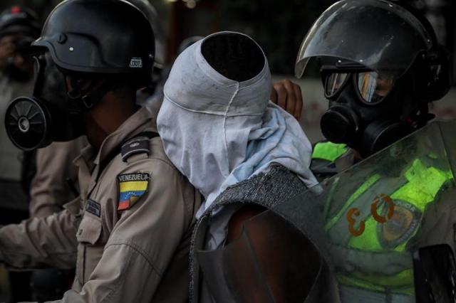 Reporteros gráficos denuncian que los cuerpos de seguridad están cubriendo los rostros de los manifestantes detenidos. Foto Miguel Gutierrez / EFE