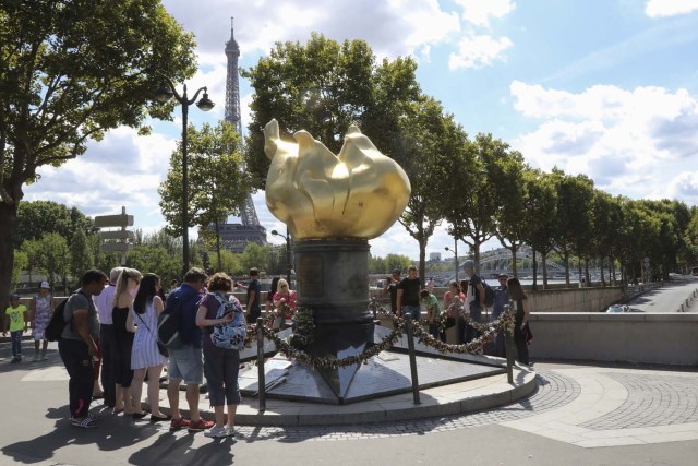 People walk around the "Flamme de la Liberté" (Liberty Flame), an original monument Princess Diana fans turned into a commemoration stele, in Paris on august 14, 2017. 20th anniversary of the death of Princess Diana in a Paris car crash will be marked on August 31, 2017. / AFP PHOTO / JACQUES DEMARTHON