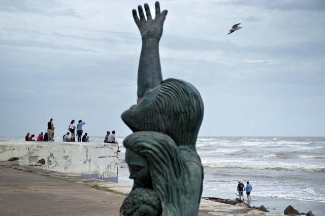 People look out from a seawall to the Gulf of Mexico as the effects of Hurricane Harvey are seen August 26, 2017 in Galveston, Texas. Hurricane Harvey left a deadly trail of devastation Saturday in Texas, as officials warned of "catastrophic" flooding and said that recovering from the most powerful storm to hit the United States in more than a decade could take years. / AFP PHOTO / Brendan Smialowski / ?The erroneous mention[s] appearing in the metadata of this photo by Brendan Smialowski has been modified in AFP systems in the following manner: [Hurricane Harvey] instead of [Hurricane Henry]. Please immediately remove the erroneous mention[s] from all your online services and delete it from your servers. If you have been authorized by AFP to distribute it to third parties, please ensure that the same actions are carried out by them. Failure to promptly comply with these instructions will entail liability on your part for any continued or post notification usage. Therefore we thank you very much for all your attention and prompt action. We are sorry for the inconvenience this notification may cause and remain at your disposal for any further information you may require.?