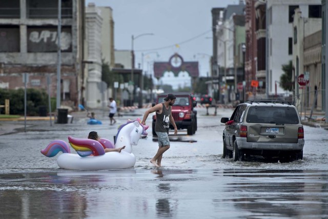 People make their way down partially flooded roads following the passage of Hurricane Harvey on August 26, 2017 in Galveston, Texas. / AFP PHOTO / Brendan Smialowski