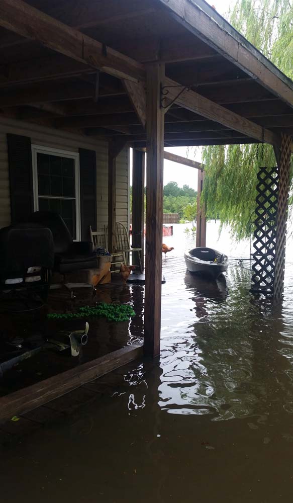 A home is pictured near Hamshire, Texas where flooding is starting to seep into the house with flood water covering the outside porch, on August 28, 2017. Monday was supposed to be the first day back at school. Instead the Magee daughters boarded a boat with their parents and floated down a Texas Interstate to rescue friends from dangerously rising flood water. "Aint nothing different than us going out on the river," mused Alissa Magee, 34, and she and husband Mike, 37, ferried Carol Brown and her four children to higher ground in Hamshire, Texas. / AFP PHOTO / Jennie MATTHEW / TO GO WITH AFP STORY by Jennie MATTHEW, "Family affair: boats to the rescue on Texas Interstate"
