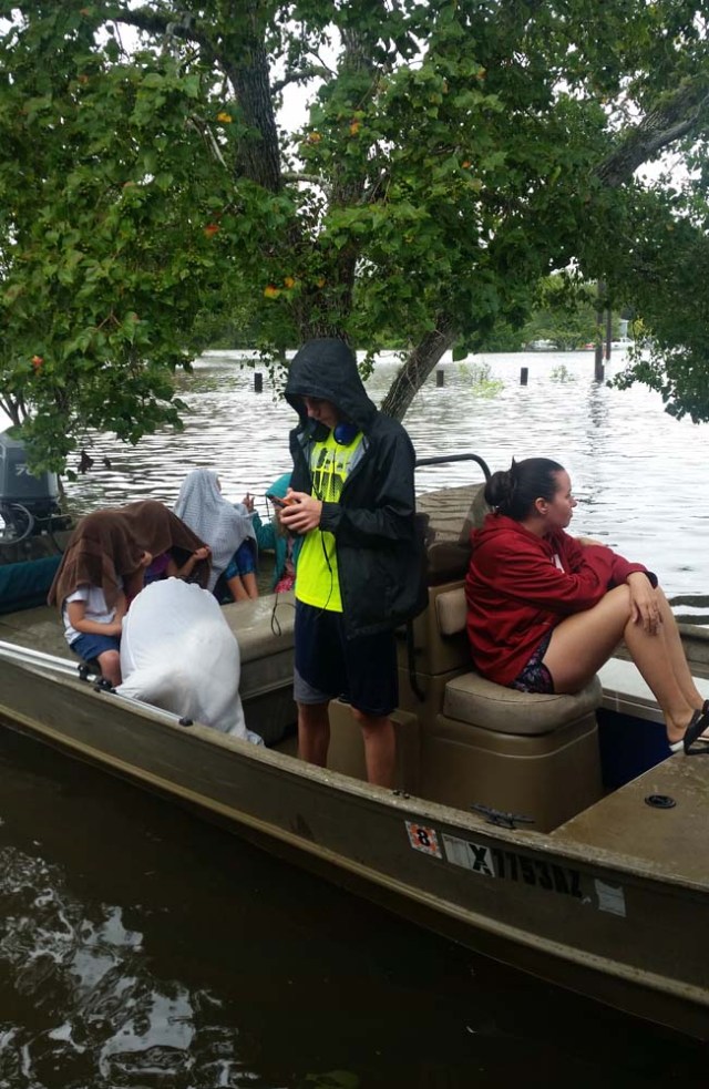 Residents sit in a boat waiting to leave with friends and volunteer rescuers to escape flooding caused by super storm Harvey near Hamshire, Texas, on August 28, 2017. Monday was supposed to be the first day back at school. Instead the Magee daughters boarded a boat with their parents and floated down a Texas Interstate to rescue friends from dangerously rising flood water. "Aint nothing different than us going out on the river," mused Alissa Magee, 34, and she and husband Mike, 37, ferried Carol Brown and her four children to higher ground in Hamshire, Texas. / AFP PHOTO / Jennie MATTHEW / TO GO WITH AFP STORY by Jennie MATTHEW, "Family affair: boats to the rescue on Texas Interstate"