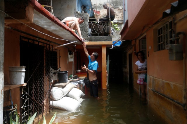 A man passes a drink to a neighbour while standing in the flooded passage of a block of flats, after the passing of Hurricane Irma, in Havana, Cuba September 10, 2017. REUTERS/Stringer NO SALES. NO ARCHIVES