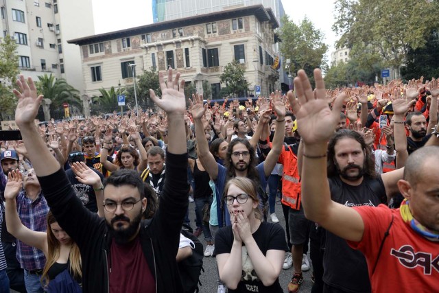 Protesters raise their hands as they gather during a general strike in Barcelona called by Catalan unions on October 3, 2017. Large numbers of Catalans are expected to observe a general strike today to condemn police violence at a banned weekend referendum on independence, as Madrid comes under growing international pressure to resolve its worst political crisis in decades. / AFP PHOTO / Josep LAGO