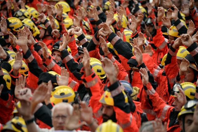 Firefighters raise their hands during a general strike in Barcelona called by Catalan unions on October 3, 2017. Large numbers of Catalans are expected to observe a general strike today to condemn police violence at a banned weekend referendum on independence, as Madrid comes under growing international pressure to resolve its worst political crisis in decades. / AFP PHOTO / Josep LAGO