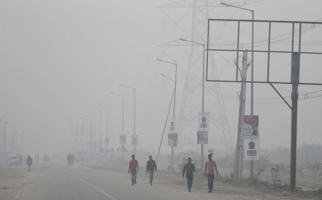 People walk through smog near Delhi, India November 13, 2017. REUTERS/Cathal McNaughton
