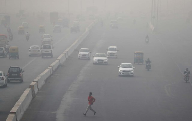 A man runs across an expressway cloaked in smog near Delhi, India November13, 2017. REUTERS/Cathal McNaughton