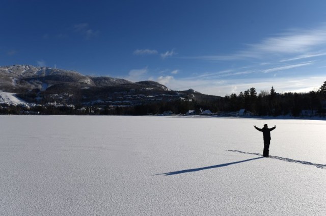 A man poses for a photo on frozen Lake Tremblant in the Laurentides region of Quebec, Canada, at the foot of the Mont Tremblant on December 24, 2017 / AFP PHOTO / Timothy A. CLARY