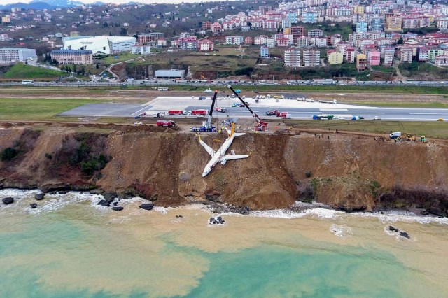 A photo made available by the Dogan New Agency shows Turkish passenger plane struck in mud on an embankment, five days after skidding off the airstrip, lifted by cranes, on January 18, 2018 . passenger plane late on January 13 skidded off the runway just metres away from the sea as it landed at Trabzon's airport in northern Turkey. The Pegasus Airlines flight, with 168 people on board, had taken off from Ankara on its way to the northern province of Trabzon. / AFP PHOTO / DOGAN NEWS AGENCY / - / Turkey OUT