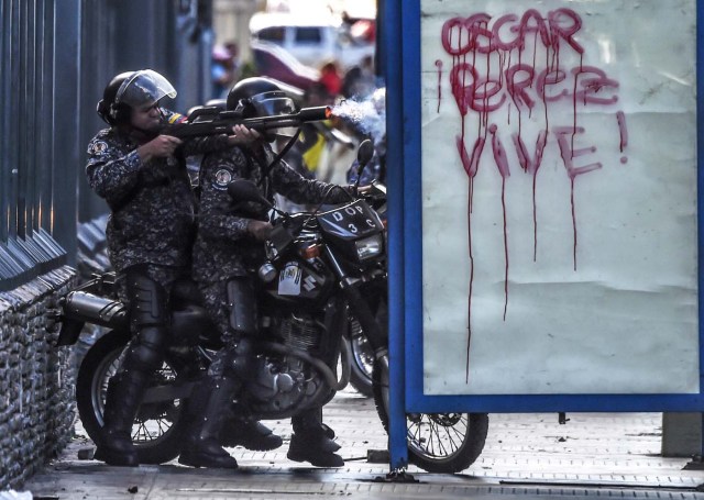 A member of the national police shoots rubber bullets during a protest in Caracas on January 22, 2018.  A demonstration in Caracas to protest the death of the insurgent Oscar Perez during an operation to capture him led Monday to clashes between demonstrators and security forces. Perez, whose body was buried by the government on January 21 against his family's wishes, was Venezuela's most wanted man since he flew a stolen police helicopter over Caracas in June dropping grenades on the Supreme Court and opening fire on the Interior Ministry.  / AFP PHOTO / JUAN BARRETO