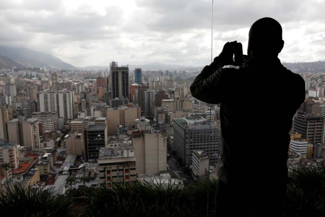 A man uses his phone to take a photo of Caracas as seen from the top of the Venezuela's Central Bank building in Caracas, Venezuela, January 31, 2018. REUTERS/Marco Bello
