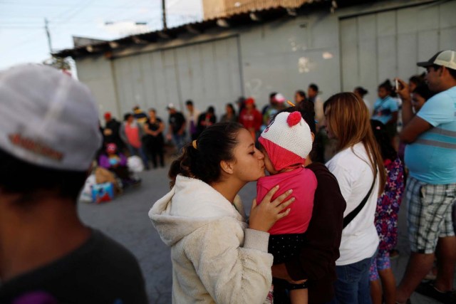 Una integrante de la caravana de inmigrantes provenientes de Centroamérica besa a un bebé mientras rezan antes de presentar un pedido de asilo en Estados Unidos, en Tijuana, México, 28 de abril de 2018. REUTERS/Edgard Garrido