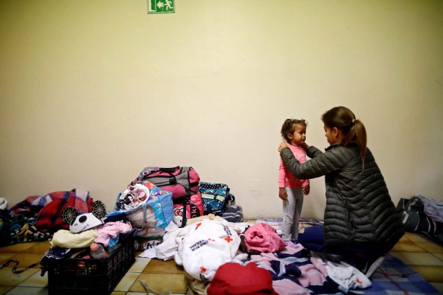A woman dresses a girl while staying at a shelter with fellow members of a caravan of migrants from Central America, prior to preparations for an asylum request in the U.S., in Tijuana, Mexico April 29, 2018. REUTERS/Edgard Garrido