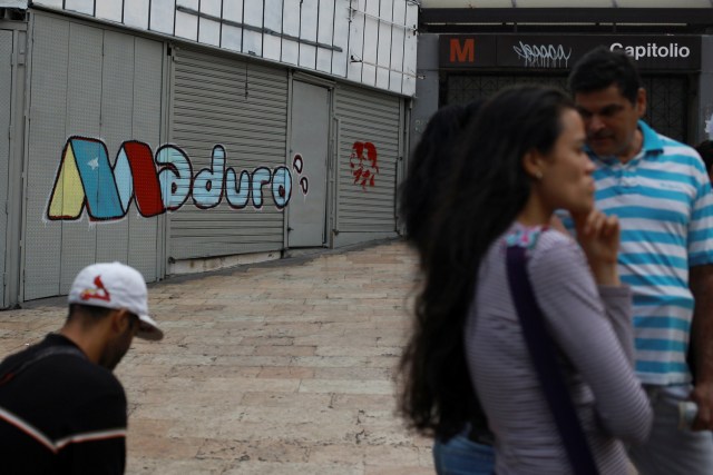 La gente se para frente a un graffiti de campaña del presidente venezolano, Nicolás Maduro, en Caracas, Venezuela, el 6 de mayo de 2018. Fotografía tomada el 6 de mayo de 2018. REUTERS / Adriana Loureiro