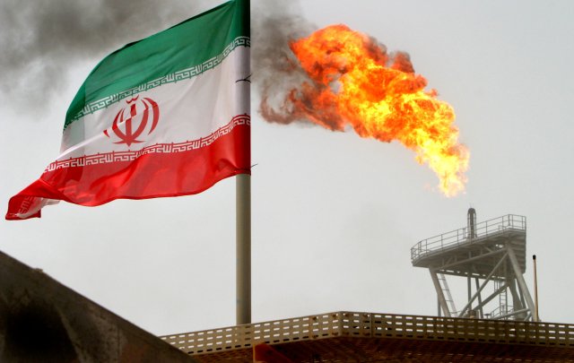 Imagen de archivo de una bandera de Irán junto a una llama en una plataforma de producción en los yacimientos de crudo de Soroush, en el Golfo Pérsico. 25 julio 2005. REUTERS/Raheb Homavandi